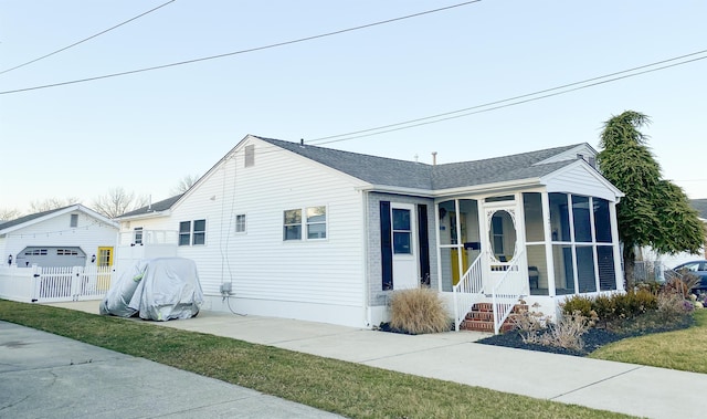 view of front of house featuring covered porch, a shingled roof, fence, a sunroom, and a gate