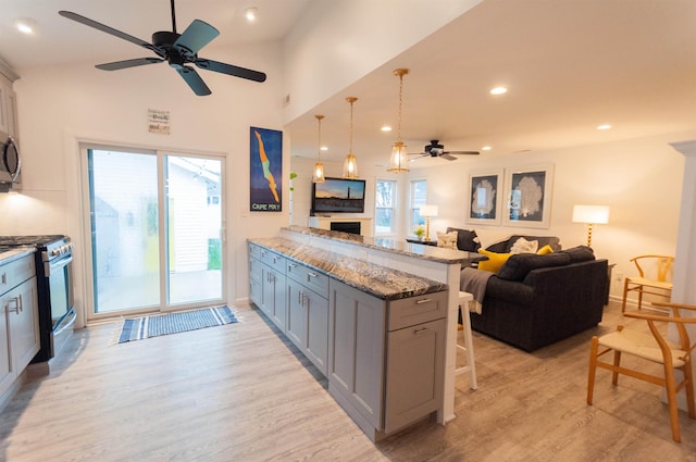 kitchen with open floor plan, stainless steel appliances, light wood-style flooring, and a kitchen breakfast bar