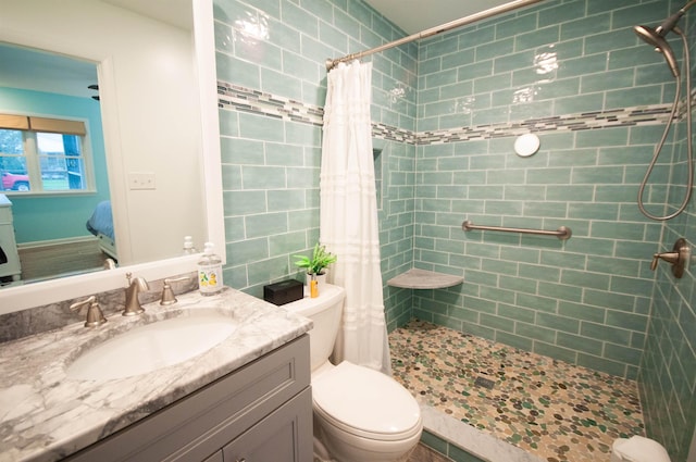 bathroom with tiled shower, vanity, and toilet