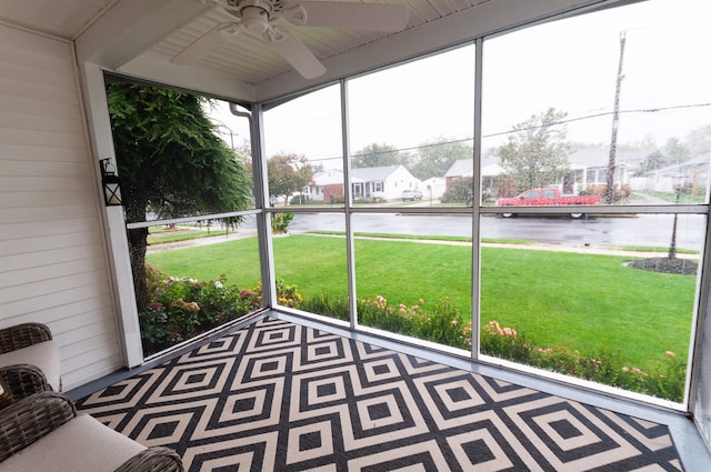 unfurnished sunroom featuring ceiling fan, a water view, and a residential view