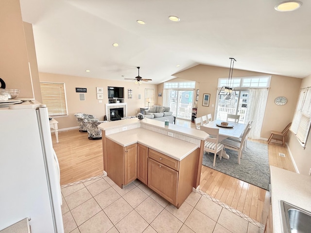 367 21st St, Avalon, NJ 08202 - kitchen featuring freestanding refrigerator, vaulted ceiling, a glass covered fireplace, light countertops, and a ceiling fan
