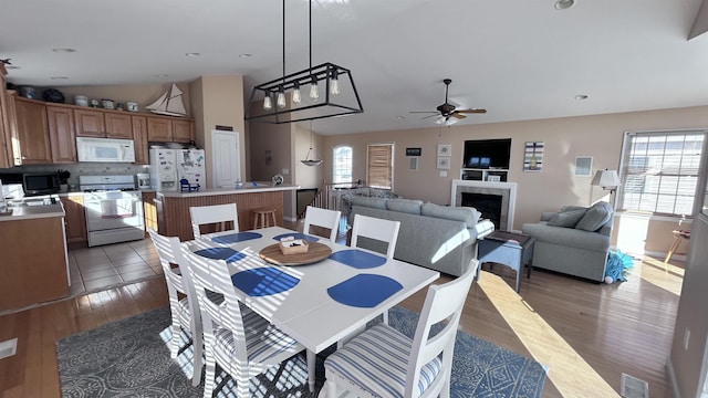 367 21st St, Avalon, NJ 08202 - dining room featuring lofted ceiling, plenty of natural light, a ceiling fan, a fireplace, and wood finished floors
