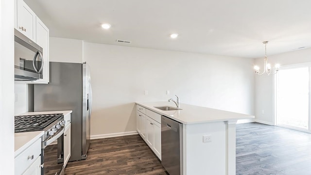 kitchen with white cabinets, appliances with stainless steel finishes, a notable chandelier, and sink