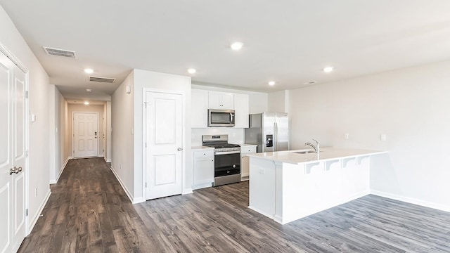 kitchen featuring a breakfast bar, white cabinets, dark hardwood / wood-style floors, and appliances with stainless steel finishes