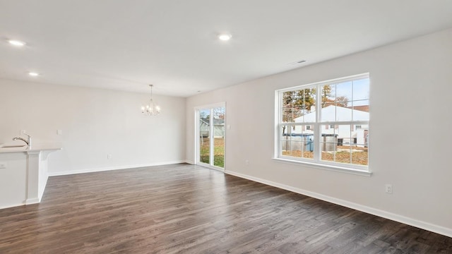 unfurnished living room with sink, dark wood-type flooring, and a chandelier