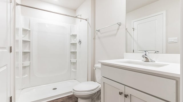 bathroom with a shower, hardwood / wood-style floors, vanity, and toilet