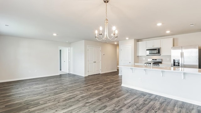 kitchen featuring a kitchen breakfast bar, stainless steel appliances, pendant lighting, an inviting chandelier, and white cabinets