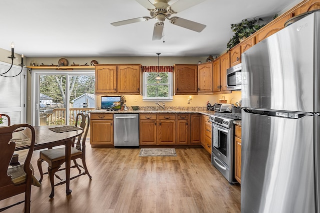 kitchen with brown cabinets, stainless steel appliances, a wealth of natural light, and light wood-type flooring