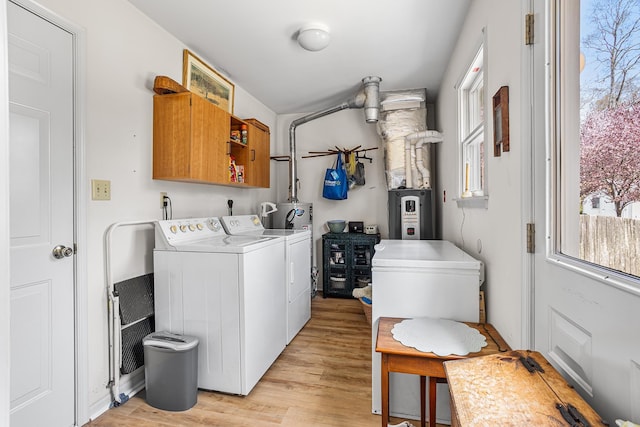 laundry room with light wood-style floors, cabinet space, washer and dryer, and a healthy amount of sunlight