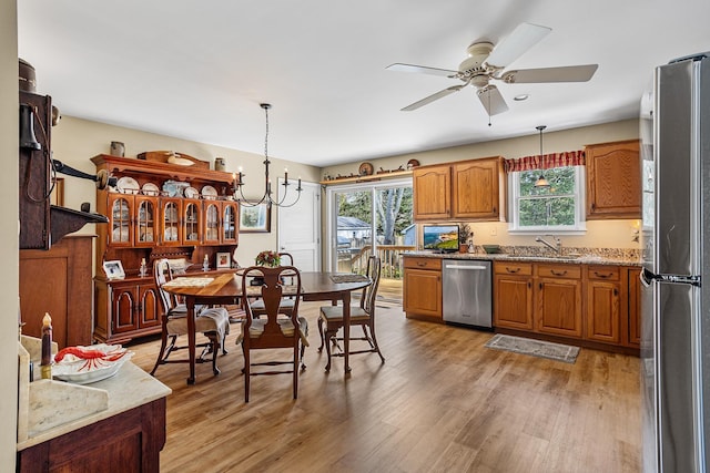 kitchen with pendant lighting, light wood finished floors, appliances with stainless steel finishes, and brown cabinets