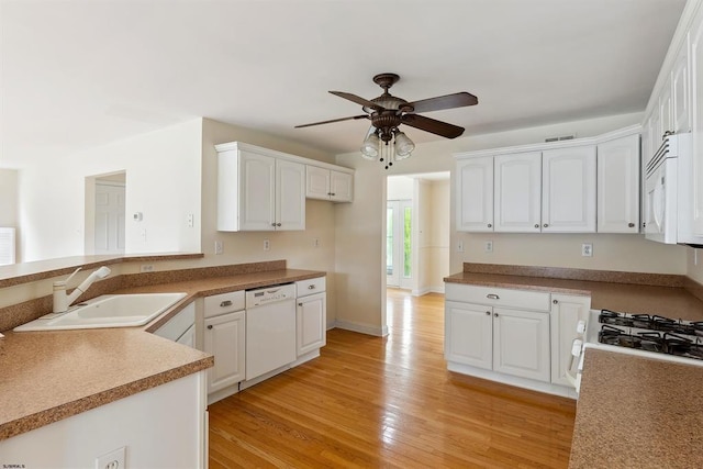 kitchen with light wood-type flooring, visible vents, a sink, white appliances, and white cabinets