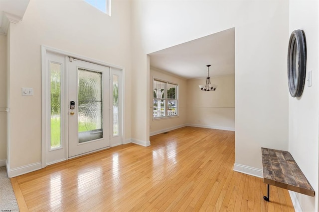 entryway featuring an inviting chandelier, baseboards, and light wood-style floors