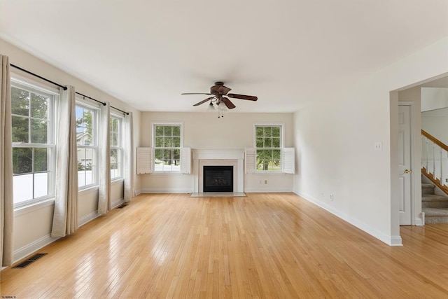 unfurnished living room featuring stairway, visible vents, baseboards, a fireplace with flush hearth, and light wood-type flooring