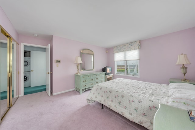 bedroom featuring baseboards, stacked washer and clothes dryer, a closet, and light carpet