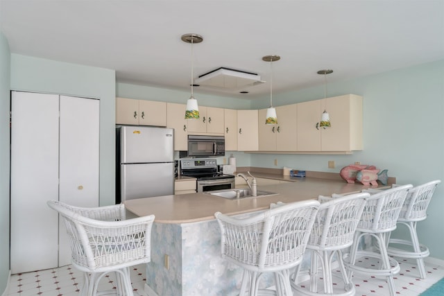 kitchen featuring a peninsula, light countertops, cream cabinets, a sink, and stainless steel appliances