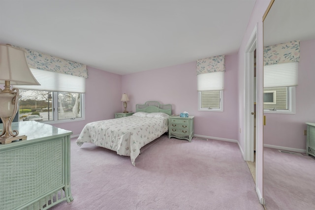 bedroom with baseboards and light colored carpet
