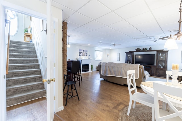 dining room featuring a paneled ceiling, stairs, a ceiling fan, and wood finished floors