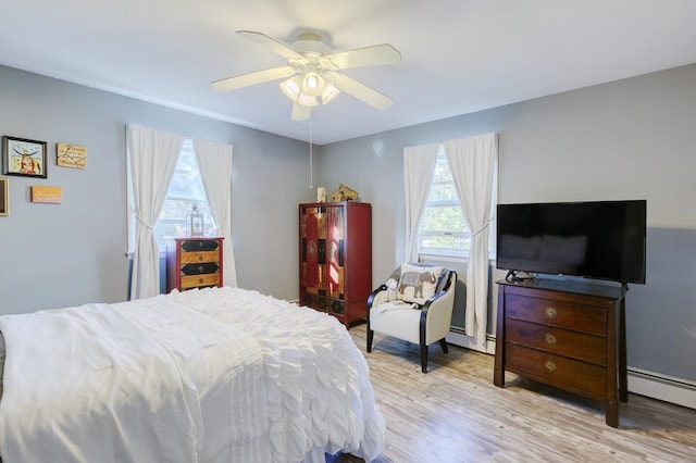 bedroom with ceiling fan, baseboard heating, and light hardwood / wood-style flooring