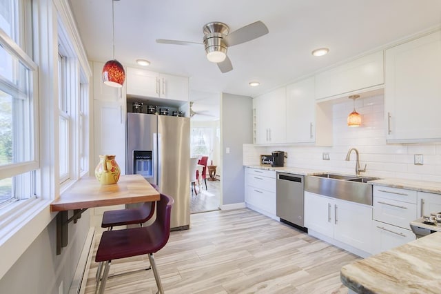 kitchen featuring white cabinetry, ceiling fan, stainless steel appliances, and decorative light fixtures