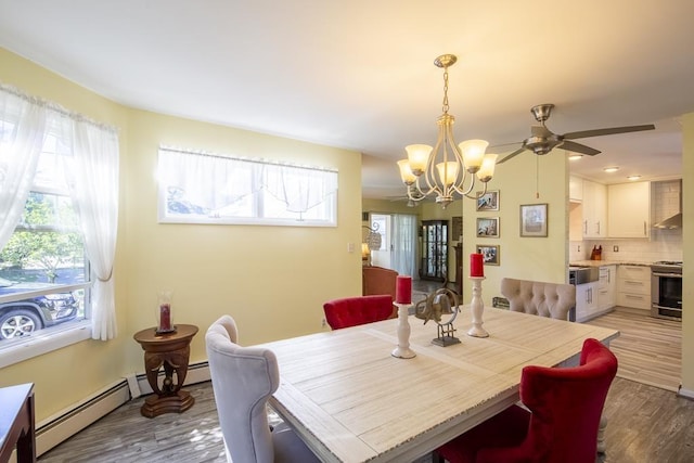 dining room with ceiling fan with notable chandelier, light hardwood / wood-style flooring, and a baseboard heating unit