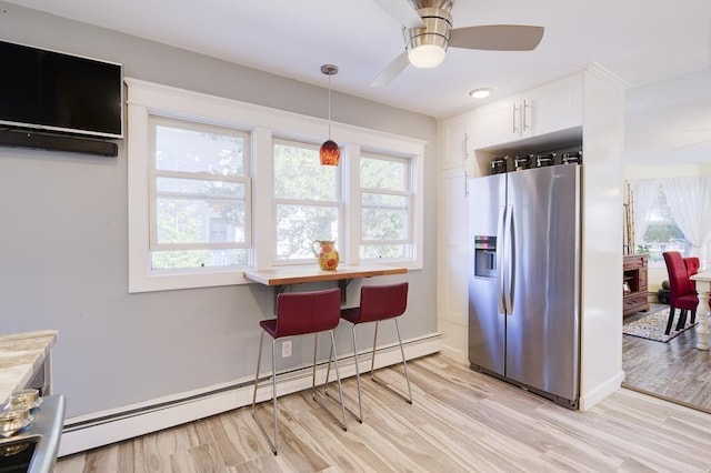 kitchen featuring a baseboard heating unit, ceiling fan, stainless steel fridge, light hardwood / wood-style floors, and white cabinetry