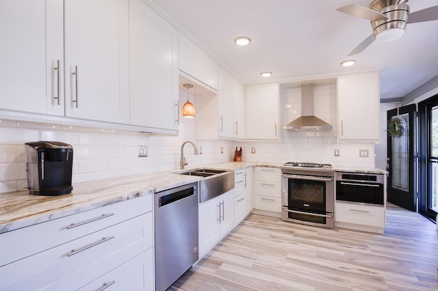 kitchen featuring white cabinets, appliances with stainless steel finishes, tasteful backsplash, and wall chimney exhaust hood