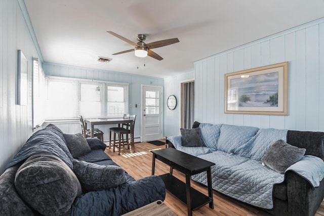 living room with ceiling fan, wood walls, and light hardwood / wood-style flooring