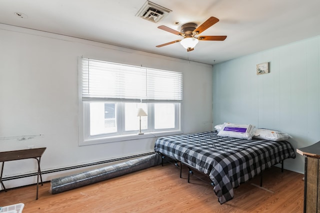 bedroom with ceiling fan, wood-type flooring, and a baseboard radiator