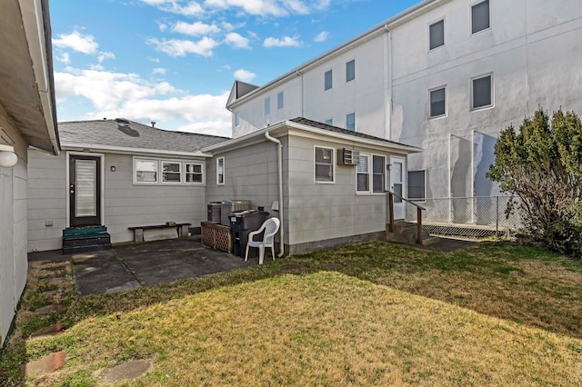 rear view of house featuring a wall mounted air conditioner, a yard, a patio, and central air condition unit