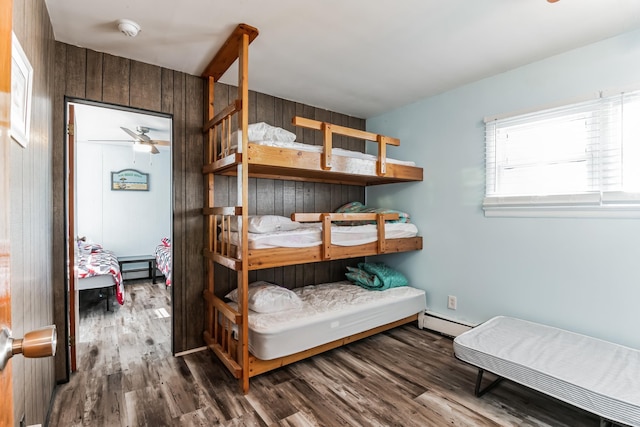 bedroom with hardwood / wood-style floors, wood walls, and baseboard heating