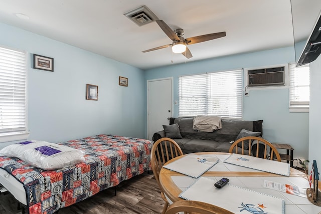 bedroom with ceiling fan, dark wood-type flooring, and a wall mounted air conditioner