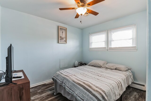 bedroom with ceiling fan, dark wood-type flooring, and a baseboard heating unit