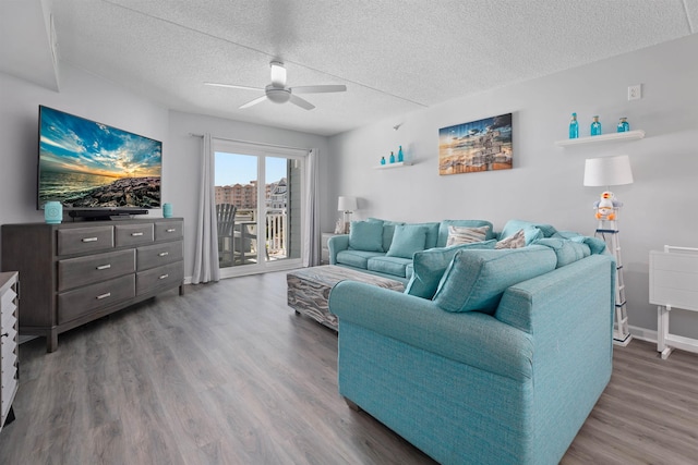 living room featuring baseboards, a textured ceiling, ceiling fan, and wood finished floors