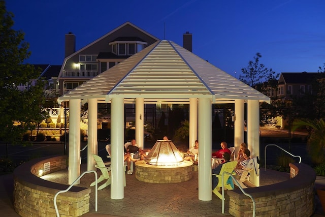 back of house at night with a patio, a gazebo, a chimney, and an outdoor fire pit