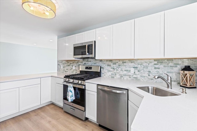 kitchen featuring a sink, light countertops, white cabinets, appliances with stainless steel finishes, and backsplash