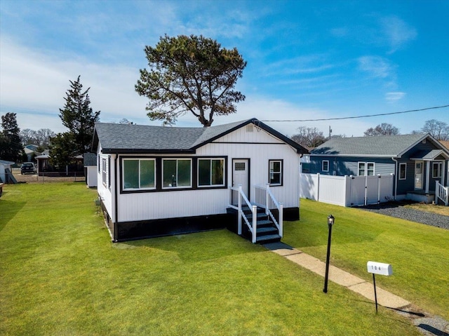 view of front of property featuring a shingled roof, a front yard, and fence