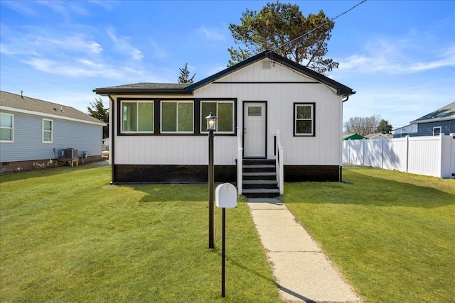 view of front of property featuring central AC unit, entry steps, a front lawn, and fence