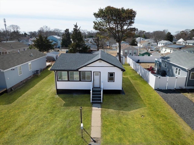 view of front of house featuring a front yard, a gate, roof with shingles, a fenced backyard, and a residential view