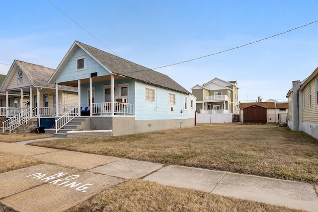 view of front of house with a front lawn, fence, a shed, covered porch, and an outdoor structure