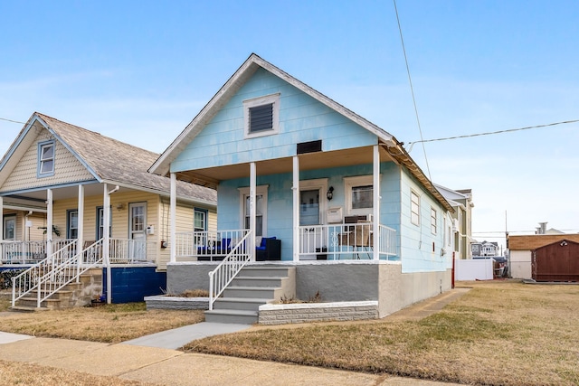 view of front of house with an outbuilding, a porch, and a front lawn