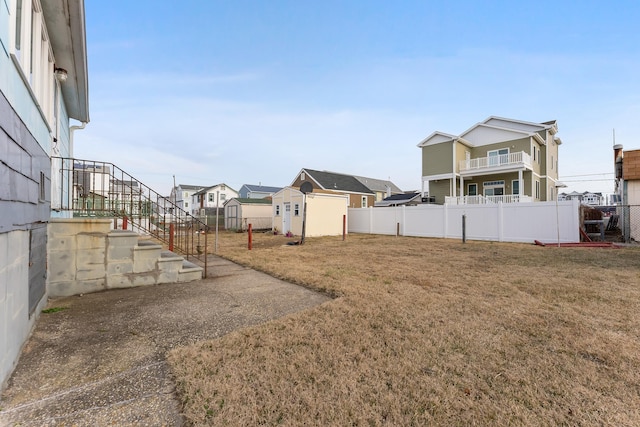 view of yard with a residential view, an outdoor structure, a shed, and fence