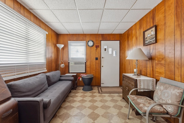 living area featuring a paneled ceiling, wood walls, and light carpet