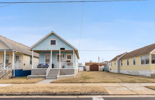 view of front of house with a storage unit, an outbuilding, a porch, and a front lawn