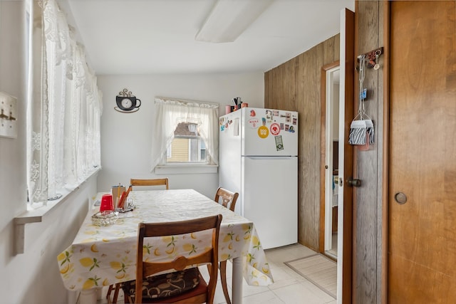 dining room with light tile patterned floors and wood walls