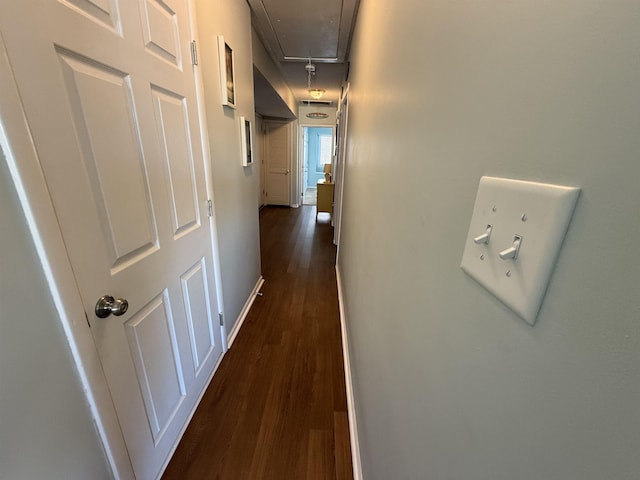 hall featuring dark wood-style floors, attic access, and baseboards