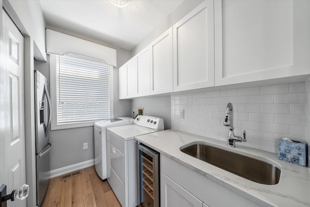 laundry area with visible vents, a sink, light wood-style floors, separate washer and dryer, and cabinet space