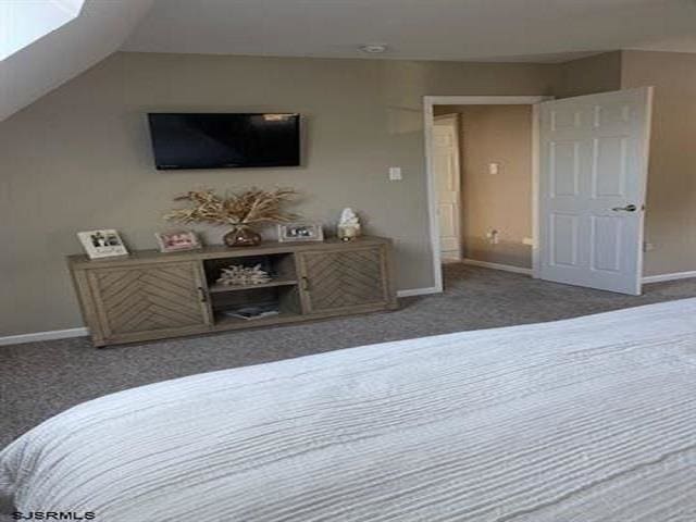 bedroom with dark carpet and vaulted ceiling