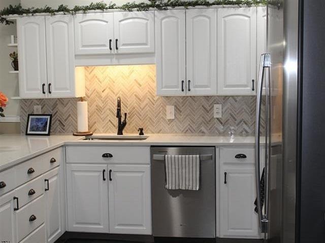 kitchen featuring white cabinets, appliances with stainless steel finishes, and backsplash