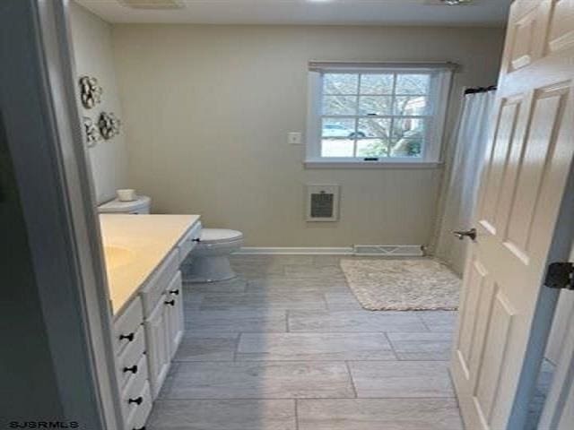 bathroom featuring vanity, toilet, and heating unit