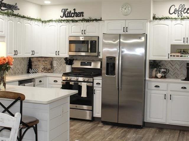 kitchen featuring decorative backsplash, stainless steel appliances, and white cabinets